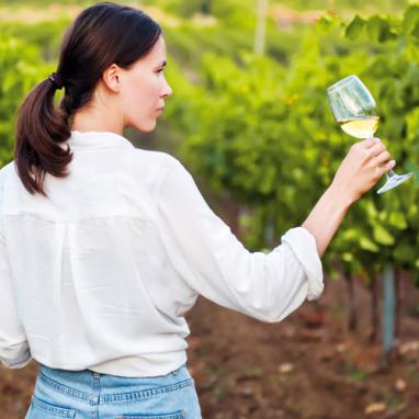 Une femme tenant un verre dans des vignes